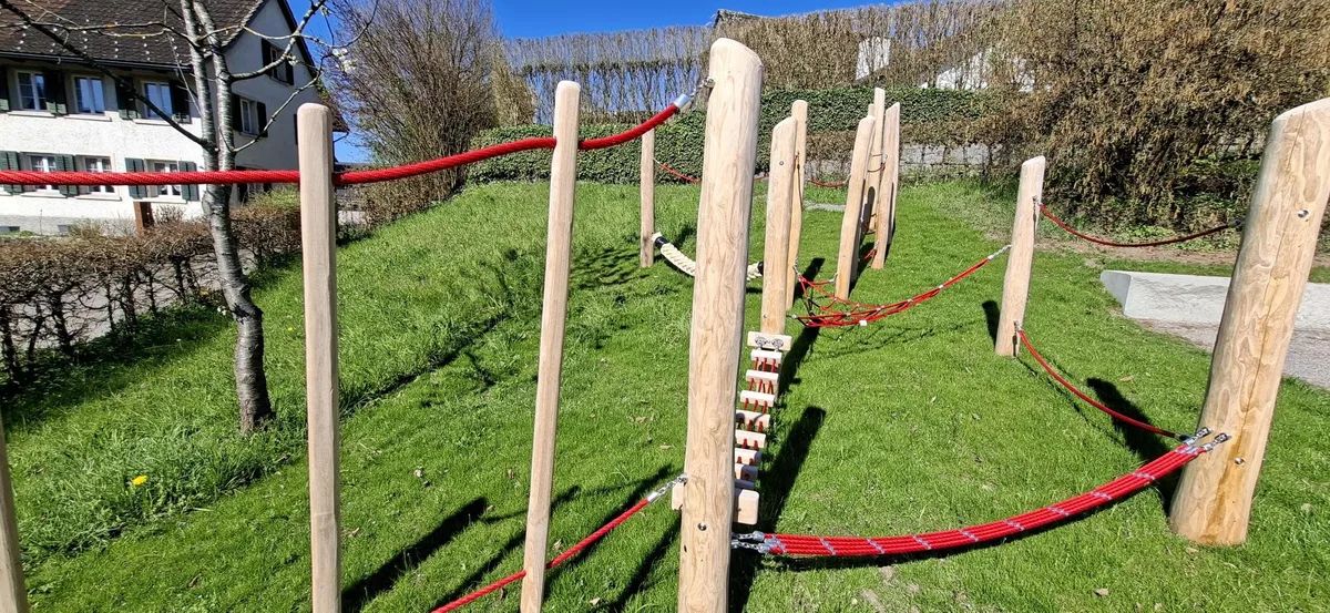 Der neue Spielplatz in Ottikon: Man sieht ein Klettergerüst mit hellem Holz und roten Seilen.